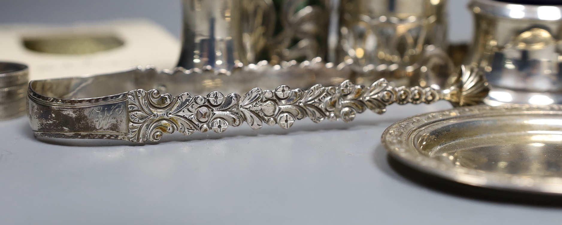A small group of collectable small silver and white metal items including two pairs of 19th century sugar tongs(one a.f.), later condiments, match sleeve, dish pill box, etc.